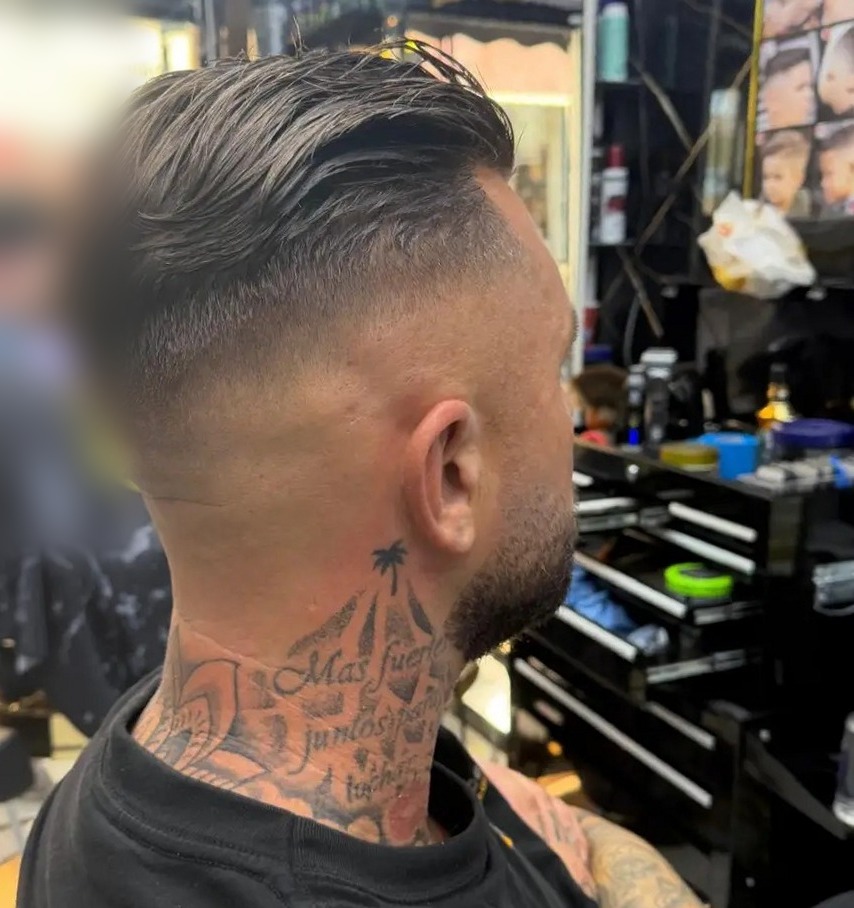 Fade met lang haar naar achteren gekamd, klant met getatoeëerde nek