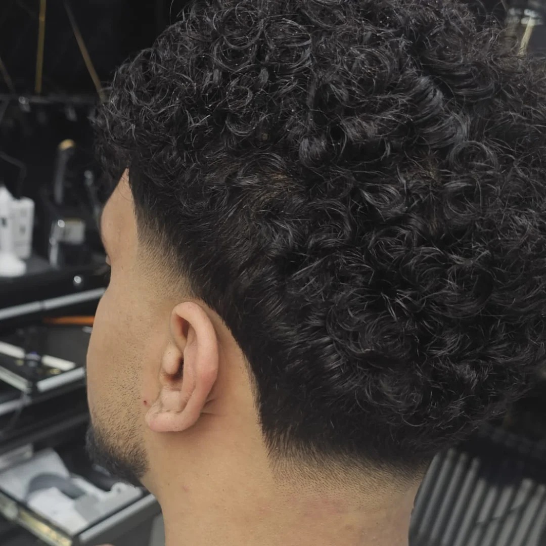 Krullend haar bovenop met een skin fade aan de zijkant